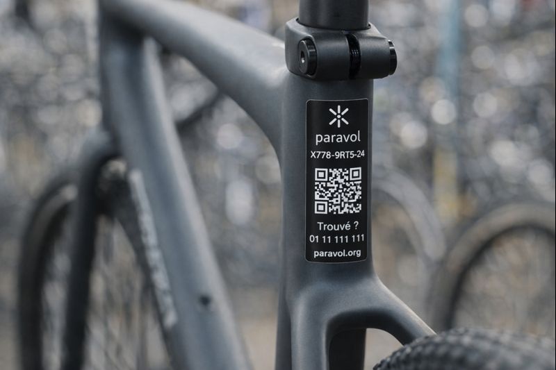 Gros plan sur le cadre en carbone d'un vélo Trek équipé d'un marquage de sécurité Paravol. L'image montre l'identifiant unique à 10 caractères et le QR code permettant l'enregistrement au fichier national (FNCUI) pour la protection contre le vol.