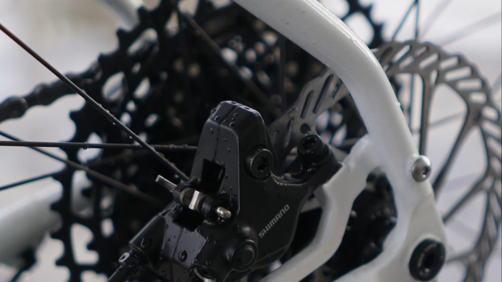 Gros plan sur un étrier de frein à disque hydraulique Shimano et son disque de frein sur un vélo de montagne blanc